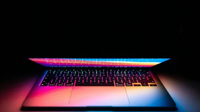 black laptop computer turned on in dim light